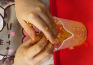 Dłonie dziecka w galaretce podczas wyciągania dinozaurów.