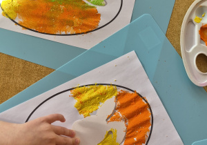 Dzieci stemplują kontur jajka, na środku jajka szablon zajączka.