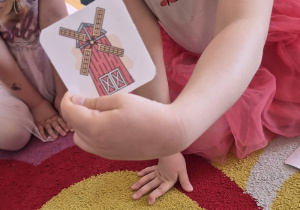 Dziewczynka pokazuje obrazek przedstawiający młyn.