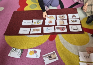 Dziecko kładzie obrazek przedstawiający jajka obok kury.