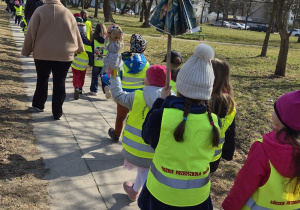 Dzieci spacerują w okolicy przedszkola z marzannami.