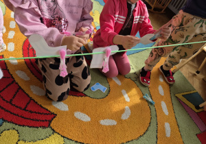 Dzieci przyczepiają klamerkami zalaminowane skarpetki do sznurka.