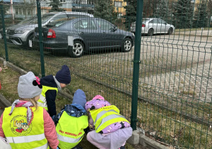 Dzieci z trawnika podnoszą śmieci.