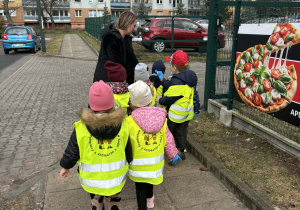 Dzieci sprzątają teren wokół przedszkola.