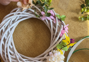 Dziecko przykleja kwiaty do wianka.