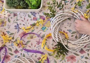 Dzieci ozdabiają wianki zielonymi gałązkami.