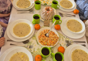 Dzieci siedzą przy wielkanocnym stole.