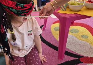 Dziewczynka próbuje podanego przez nauczyciela owocu.