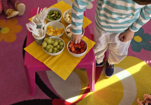 Chłopiec częstuje się truskawką.