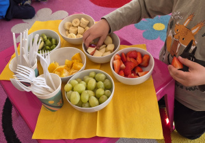 Dziecko częstuje się owocami.