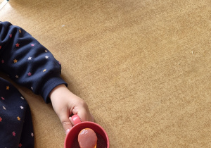 Dzieci przy stoliku jedzą mus owocowy.