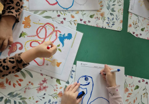 Dzieci ćwiczą grafomotowyke rysują po śladzie.