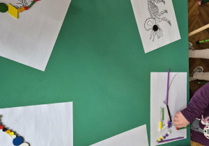 Dzieci z darów Froebla układają dinozaura na podstawie szkieletu.