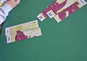 Dziecko układa pocięty na części obrazek - dinozaura.