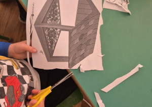 Dziecko wycina nożyczkami z papieru karmnik.