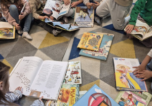 Dzieci oglądają w bibliotece wybrane książki.