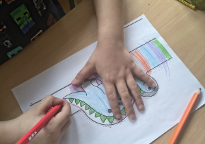 Dziecko koloruje przepaskę z dinozaurem.