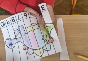 Dziecko rozcina pokolorowane już puzzle.
