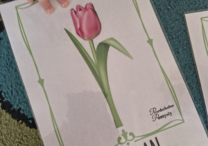 Dziewczynka wskazuje rączką kwiat tulipana.