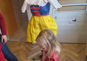 Dziewczynka wybiera elementy garderoby do przypięcia na manekinie.
