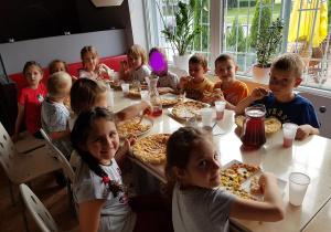 Dzieci jedzą pizzę