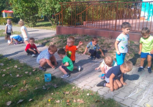 - Dzieci rysują kredą po chodniku przedszkolnym