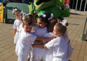 - Dzieci przytulają się do kogoś przebranego za ogromną żabę