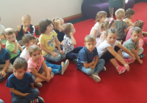 - Dzieci siedzą na podłodze w Pałacu Młodzieży i czekają na przedstawienie