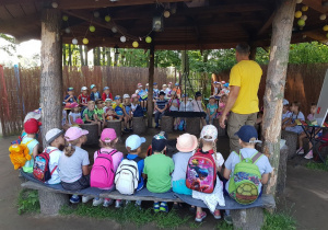 Dzieci siedzą w kole i słuchają prelekcji.