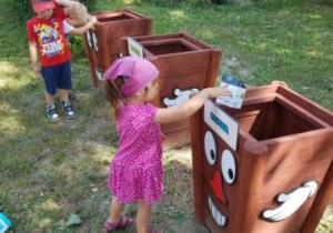 Dziewczynka wyrzuca kartonowe pudełko do kosza na papier.