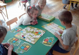 Dzieci grają w grę planszową dot. segregacji śmieci.