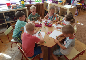 Dzieci siedzą przy stole, samodzielnie rysują źródła odnawialne.