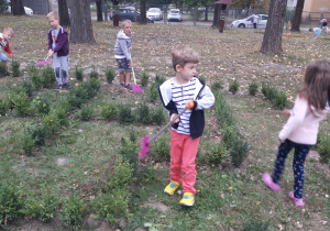 Dzieci grabią liście w labiryncie z bukszpanu.