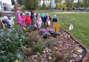 Dzieci pozują do zdjęcia oglądając kwiaty.