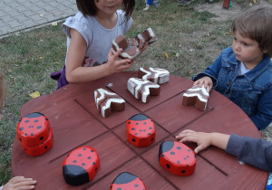 Dzieci grają w kółko krzyżyk drewnianymi owadami