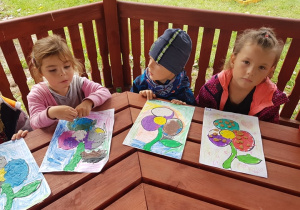 Dzieci prezentują swoje prace w altanie przedszkolnej.