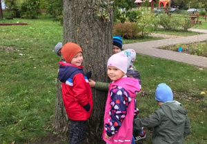 Dzieci pozują przy drzewie.