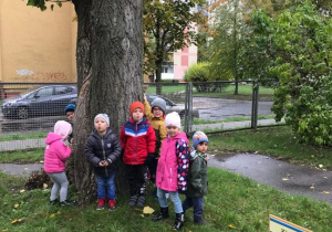 Dzieci pozują przy drzewie.