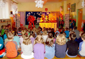Dzieci siedzą tyłem i patrzą w kierunku dekoracji do przedstawienia