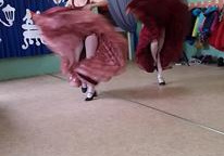 Dwie tancerki w długich sukniach tańcząc unoszą je do góry.