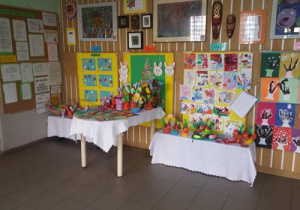 Ogólny plan kiermaszu – stoły z ozdobami przygotowanymi przez dzieci a na ścianach prace dzieci na kolorowych tłach.