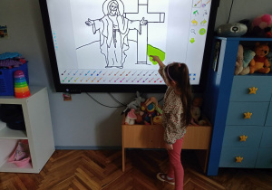Dziewczynka na monitorze interaktywnym koloruje obrazek.