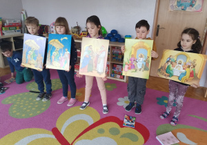 Dzieci stoją w rzędzie i trzymają obrazy ułożonej historyjki obrazkowej.