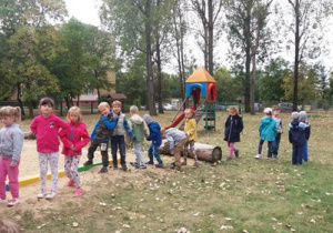 Dzieci w ogrodzie stoją wzdłuż piaskownicy.