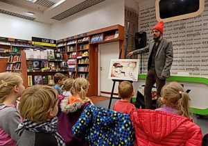 Dzieci przyglądają się rysunkowi umieszczonemu na sztaludze.