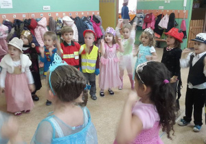 Dzieci przebrane w kostiumy z bajek podnoszą ręce do góry.