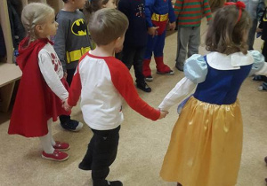 Dzieci stojąc w kole trzymają się za ręce.