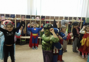 Dzieci w strojach unoszą ręce do góry. Na pierwszym planie Halk, myszka, superman.