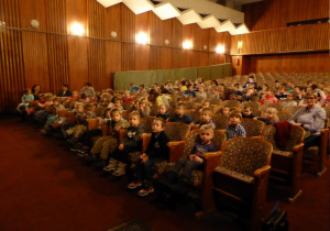 Dzieci wygodnie siedzą w fotelach w teatrze