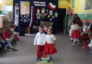 Chłopiec z dziewczynką tańczą w strojach o barwach narodowych